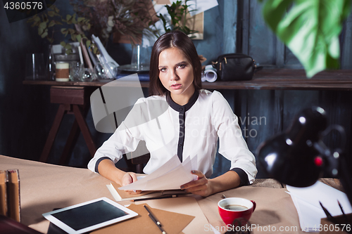 Image of Young beautiful woman working with cup of coffee