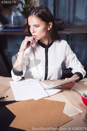 Image of Young beautiful woman working with cup of coffee