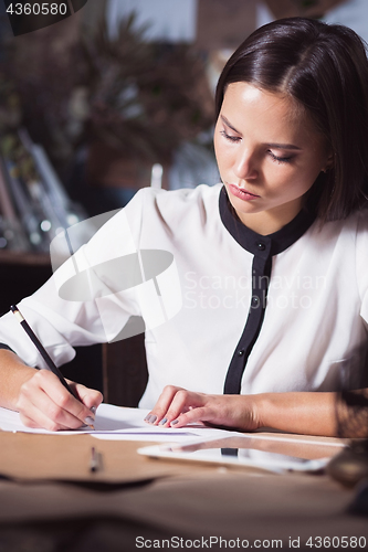 Image of Young beautiful woman working with cup of coffee