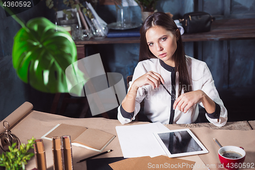 Image of Young beautiful woman working with cup of coffee