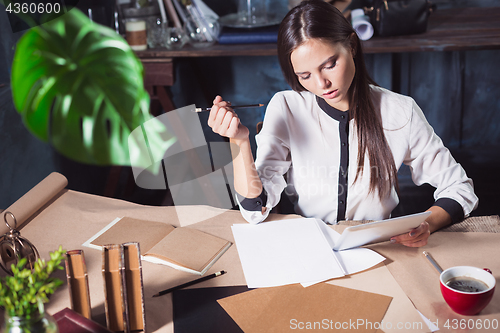 Image of Young beautiful woman working with cup of coffee