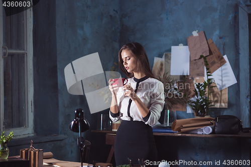 Image of Young beautiful woman working with cup of coffee