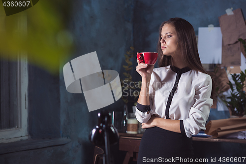 Image of Young beautiful woman working with cup of coffee