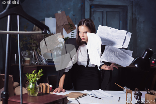 Image of Young business woman throwing documents at camera.