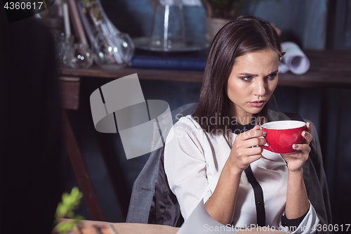 Image of Young beautiful woman working with cup of coffee