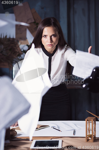 Image of Young business woman throwing documents at camera.