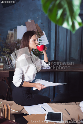 Image of Young beautiful woman working with cup of coffee