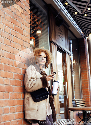 Image of young pretty african american women drinking coffee outside in c