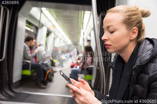 Image of Young girl reading from mobile phone screen in metro.