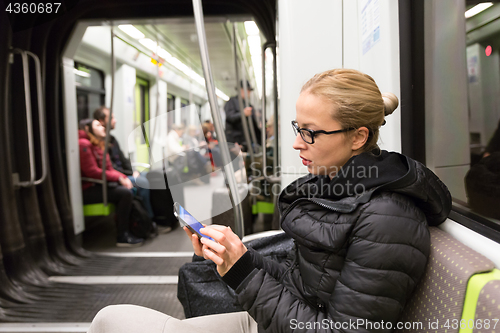 Image of Young girl reading from mobile phone screen in metro.