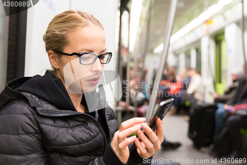 Image of Young girl reading from mobile phone screen in metro.