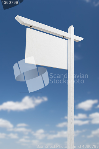 Image of Blank Real Estate Sign Over A Blue Sky with Clouds.