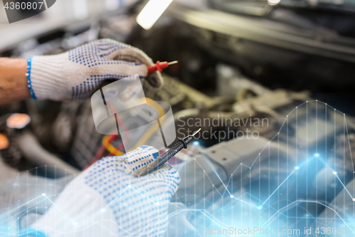 Image of auto mechanic man with multimeter testing battery
