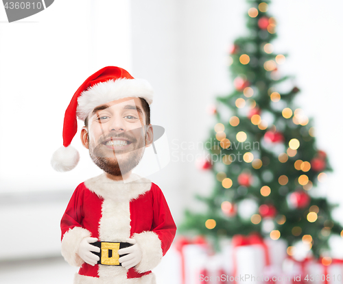 Image of smiling man in santa costume over christmas tree