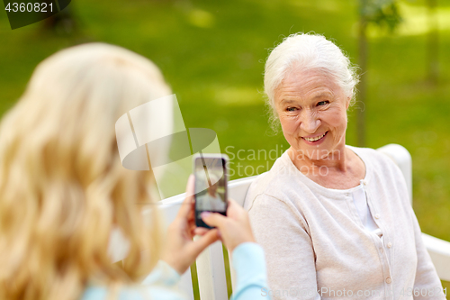 Image of daughter photographing senior mother by smartphone