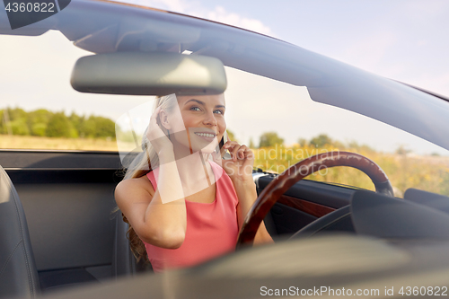 Image of woman calling on smartphone at convertible car
