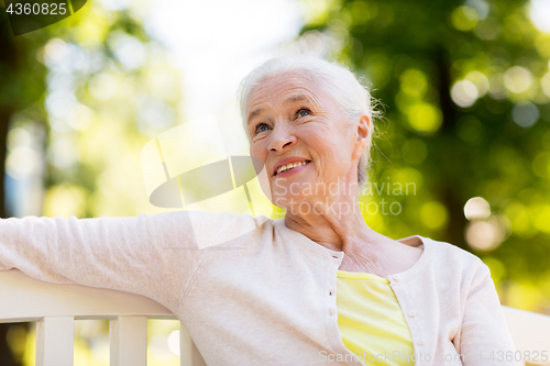 Image of happy senior woman sitting on bench at summer park