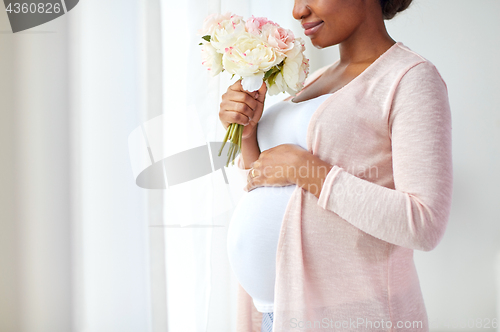 Image of happy african american pregnant woman with flowers