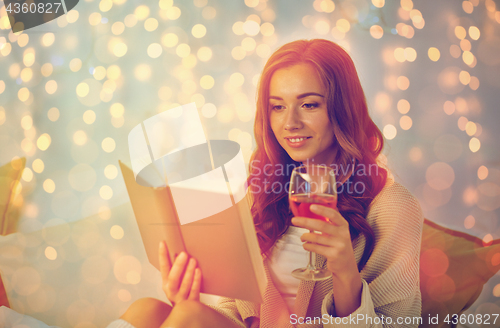 Image of happy young woman reading book in bed at home