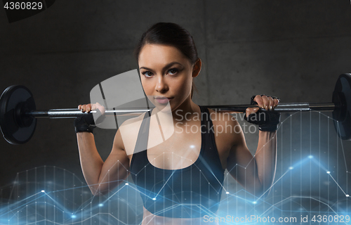 Image of young woman flexing muscles with barbell in gym