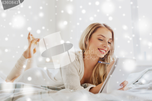 Image of happy young woman with notebook in bed at home