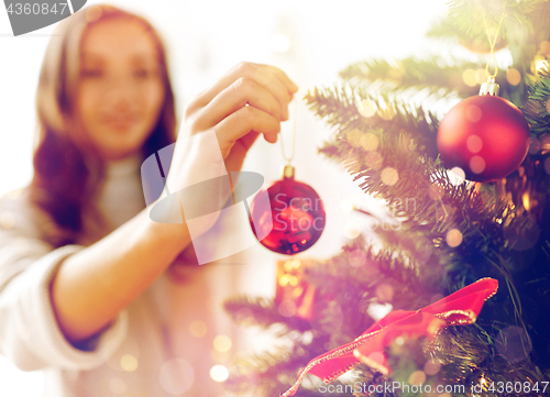 Image of happy young woman decorating christmas tree