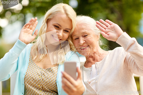 Image of daughter and senior mother taking selfie at park