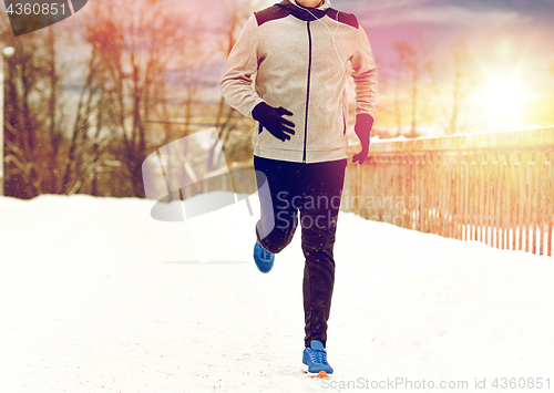 Image of man in earphones running along winter bridge