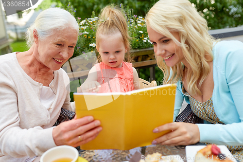 Image of happy family reading book at cafe terrace