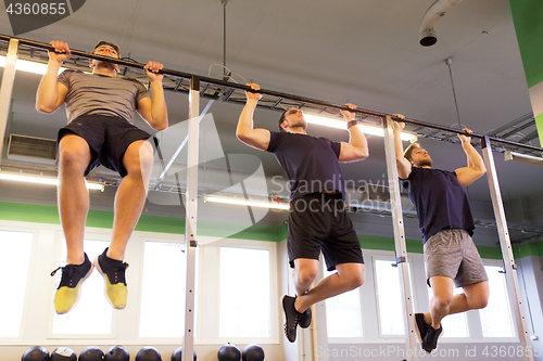 Image of group of young men doing pull-ups in gym