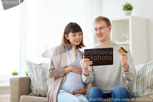 Image of husband and pregnant wife shopping online at home