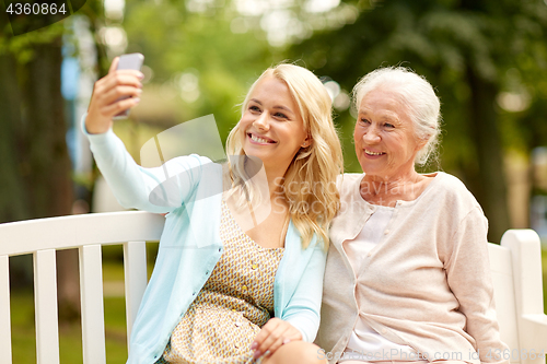 Image of daughter and senior mother taking selfie at park