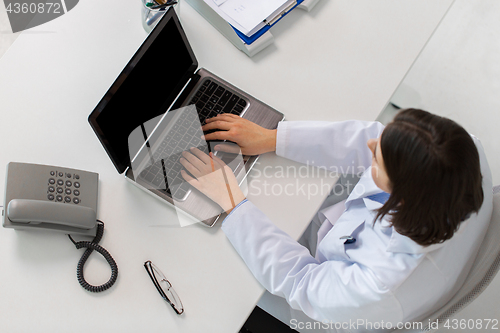 Image of woman doctor typing on laptop at clinic