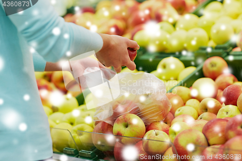 Image of woman with bag buying apples at grocery store