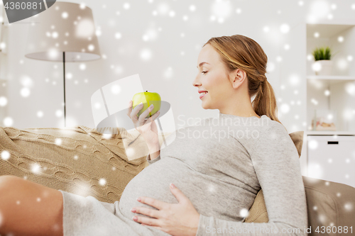 Image of happy pregnant woman with green apple