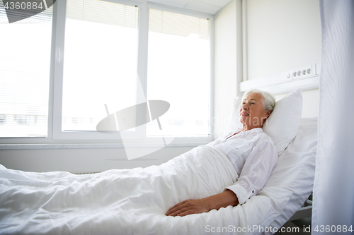 Image of smiling senior woman lying on bed at hospital ward