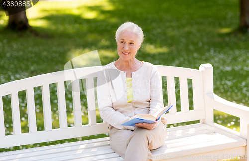 Image of happy senior woman reading book at summer park