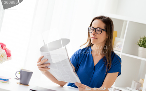 Image of businesswoman reading newspaper at office