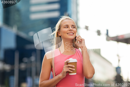 Image of woman with coffee calling on smartphone in city