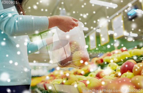 Image of woman with bag buying apples at grocery store