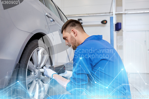 Image of mechanic with screwdriver changing car tire