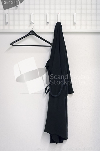 Image of a black bathrobe is hanging at the wardrobe