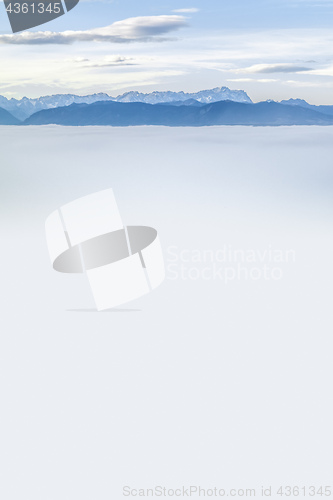 Image of landscape covered in fog with the alps in the background