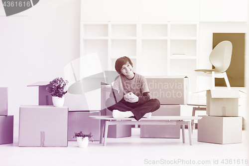 Image of boy sitting on the table with cardboard boxes around him