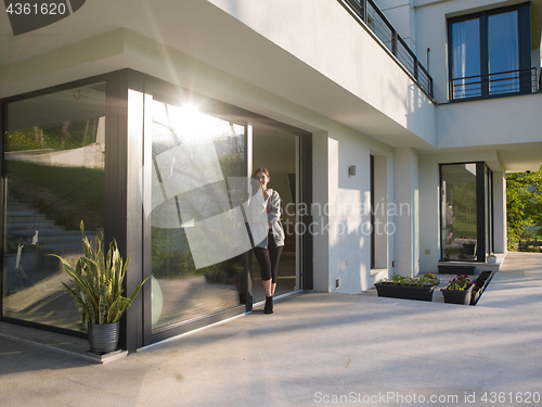 Image of woman drinking coffee in front of her luxury home villa