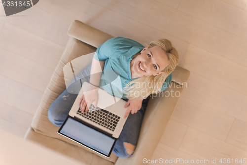 Image of Young woman using laptop at home top view