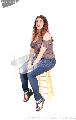 Image of Young woman sitting on a bar chair, smiling