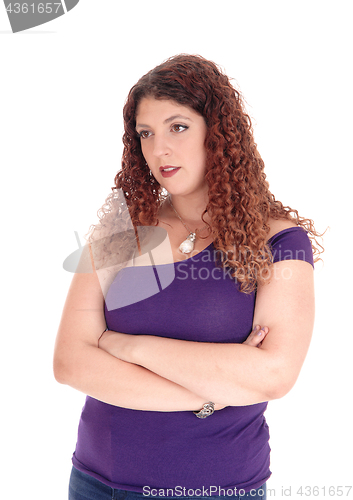 Image of Young woman standing with arms crossed looking away