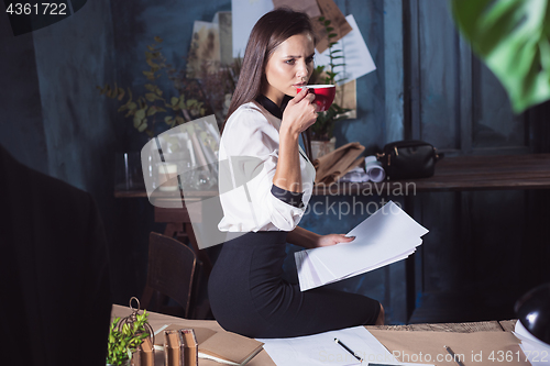 Image of Young beautiful woman working with cup of coffee