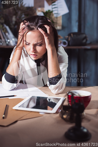 Image of Young frustrated woman working at office desk in front of laptop